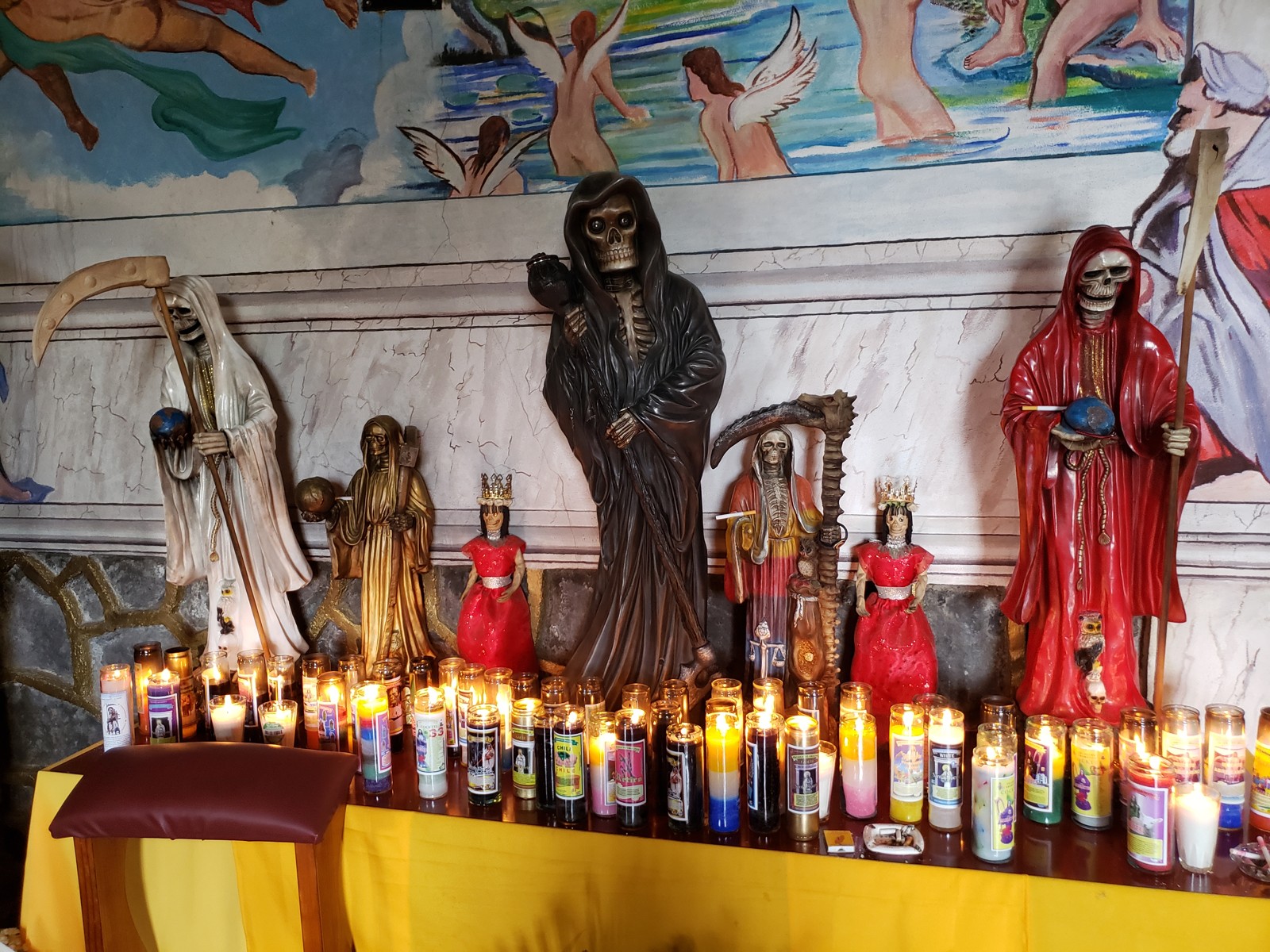 Rows of lit votive candles and Santa Muerte figures at the Michoacán temple.